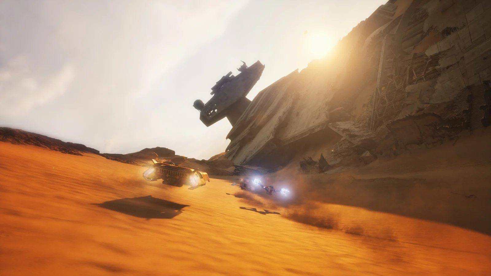 A speeder races through a sunlit desert beneath a wrecked starship
